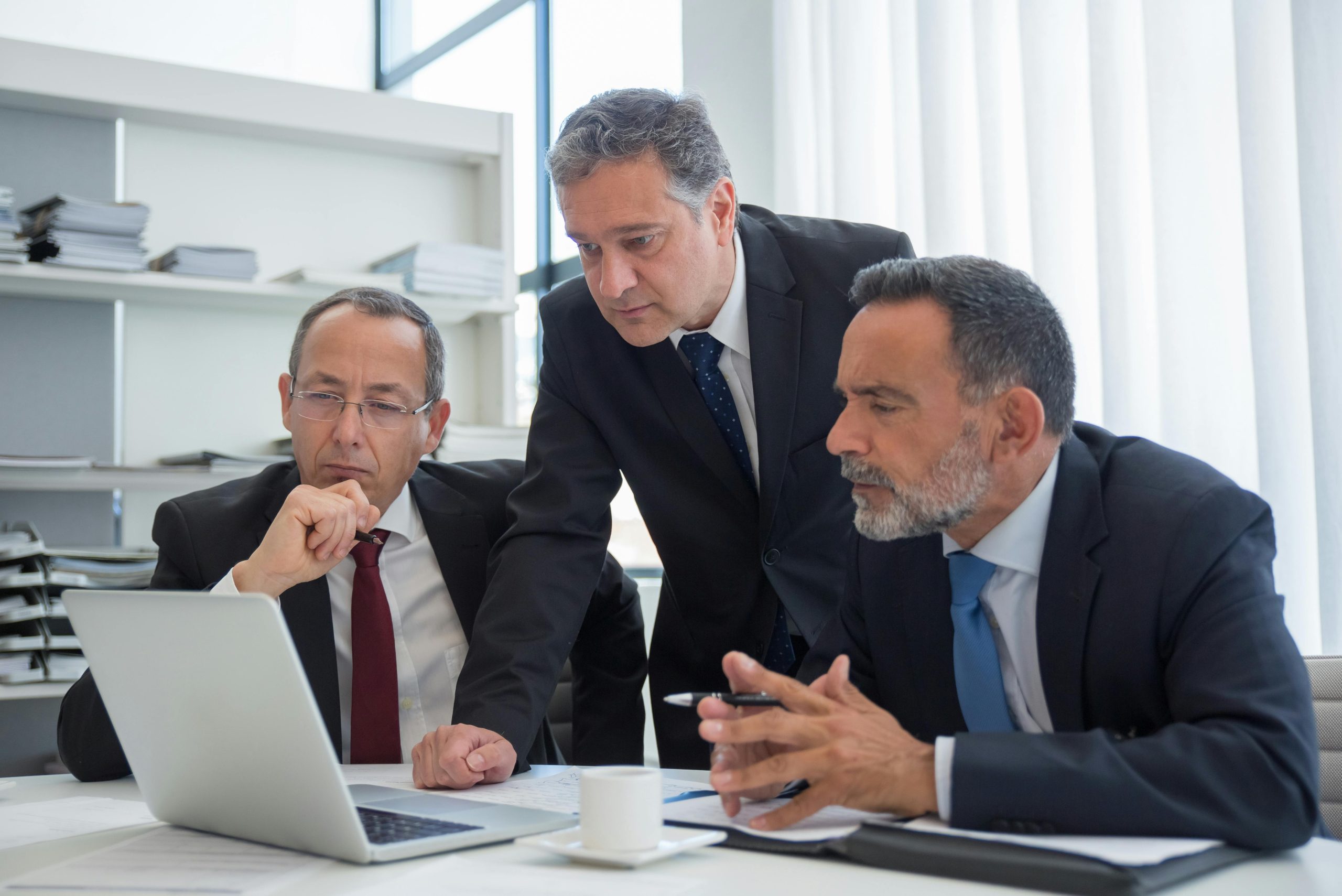 Three directors discussing over a laptop.